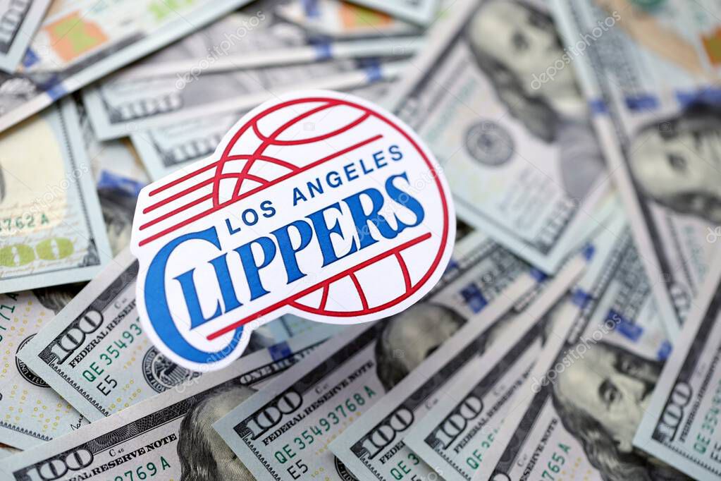 KYIV, UKRAINE - FEBRUARY 23, 2025 Los Angeles Clippers basketball team badge lies on big amount of hundred US dollar bills close up