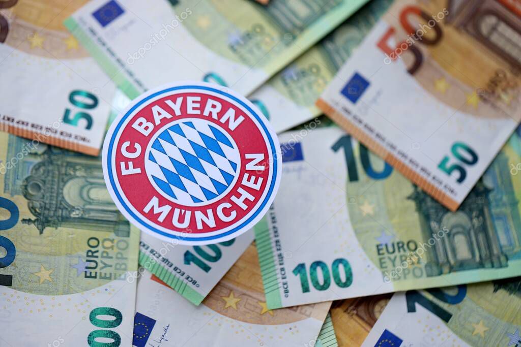 KYIV, UKRAINE - FEBRUARY 23, 2025 FC Bayern Munich football club badge lies on big amount of hundred EURO money bills