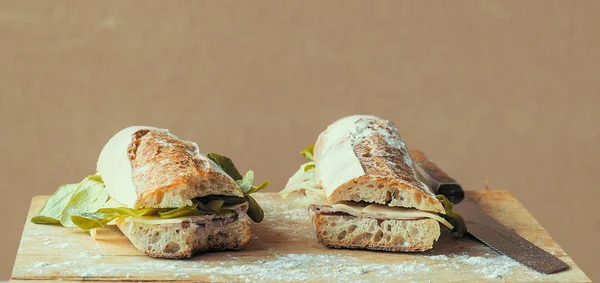 Stokbrood Snijden Twee Gebeten Gevuld Met Kaas Salade Gebakken Ham — Stockfoto