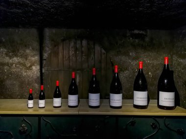 Bottles of different sizes in a French wine cellar clipart