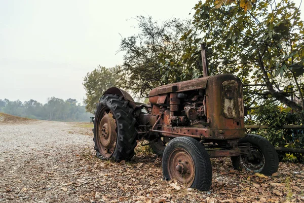 Old tractor on a pebble beach by a river