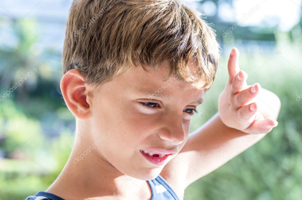 Little boy covers his face from the sun's rays