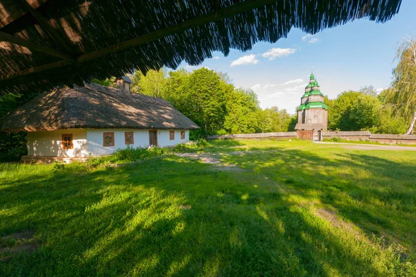 Una gran cabaña ucraniana en el fondo de una iglesia de madera en la distancia —  Fotos de Stock