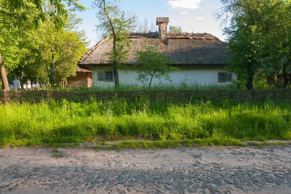 Stone road passerar nära gamla ukrainska huset med en flätade staket och en grönskande trädgård — Stockfoto