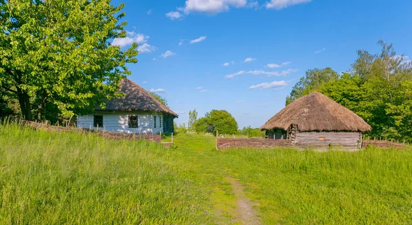 Autentyczny drewniany dom pokryty stroiki na podwórku pod błękitnym niebem — Zdjęcie stockowe