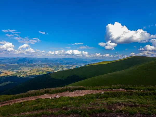 Nuvens brancas no céu azul flutuando acima dos picos da montanha que se estendem até a linha do horizonte — Fotografia de Stock