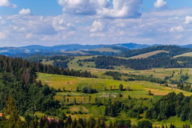 Dağ araziler ve renkli alanlar mavi gökyüzü beyaz bulutlar ile karşı