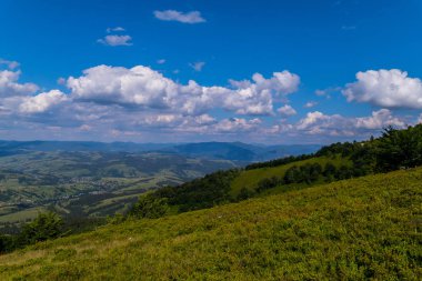 Ismarlayarak yeşil yamaç üzerinden uzaktan küçük beyaz noktalar olması için görünen bir dağ vadisinde yalan evler.