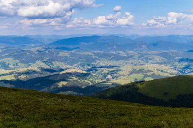 Yeşil alanlar, yaprak döken ormanlar ve büyük bir dağ zirvesine eteğindeki küçük bir kırsal köy