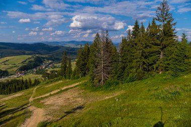 Mesafe ve yeşil dağların evlerde ufukta için nazik bir yamaç üzerinde küçük bir yol