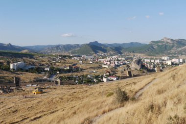 parçalanmış bir kale, bir sirk ve evler bir dağ Vadisi, Kuru ot yer. Turizm