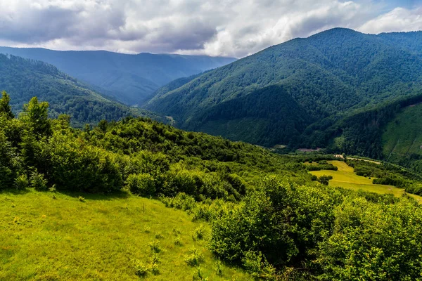 Un hermoso paisaje de picos montañosos está cubierto de bosques verdes y densos de abetos, llegando a las cimas de las nubes. Ratones perfectos para caminatas extremas —  Fotos de Stock