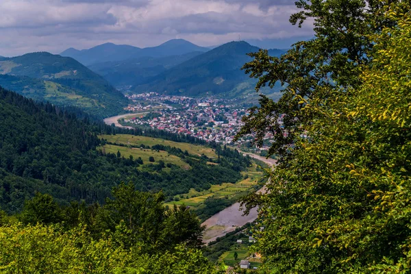 Eine gemütliche Stadt umgeben von Bergen am Ufer eines kleinen Gebirgsflusses — Stockfoto