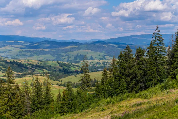 Grenzenlose grüne Ebenen mit kleinen Bergen in der Ferne und Bauernhäusern dazwischen — Stockfoto