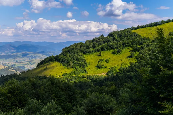 Cielo azul con nubes sobre una montaña cubierta de espesos arbustos y árboles — Foto de Stock