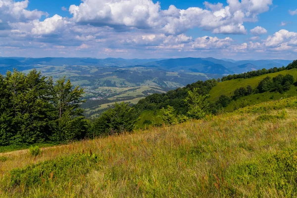 Ein großes ländliches Dorf mit kleinen Häusern liegt im Tal der malerischen grünen Berge — Stockfoto