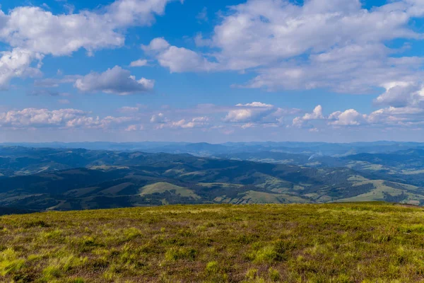 Vista do topo da montanha nas extensões ilimitadas de montanhas e colinas de verde Cárpatos com céu azul — Fotografia de Stock