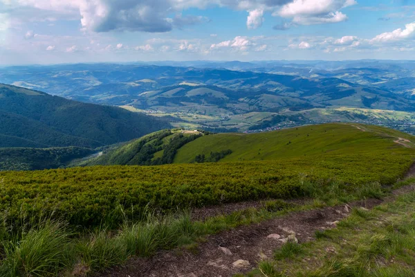 Estrada da montanha que conduz à descida de uma colina alta contra o céu azul — Fotografia de Stock