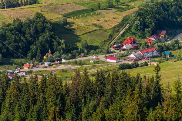 Uma aldeia resort com grandes edifícios, pequenas casas e um templo de madeira no sopé das altas montanhas verdes — Fotografia de Stock