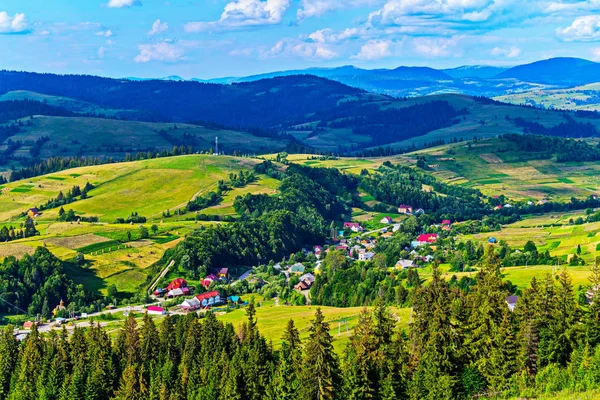 Leuchtend rote Dächer von Häusern, die sich zwischen den grünen Hügeln der Karpatenstadt ausbreiten — Stockfoto