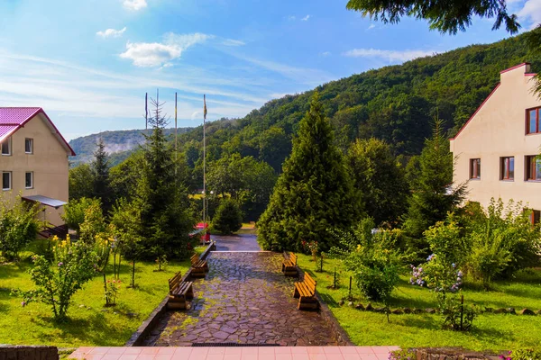 Befeuchten Sie den steinigen Weg mit Bänken zwischen den Gebäuden der Hotelanlage in den Bergen nach dem Regen — Stockfoto