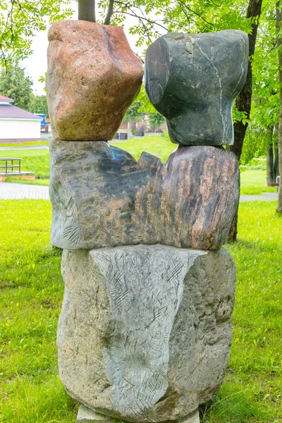 Düzgün kesilmiş yeşil çim arka planı büyük kayalar ile taş heykel