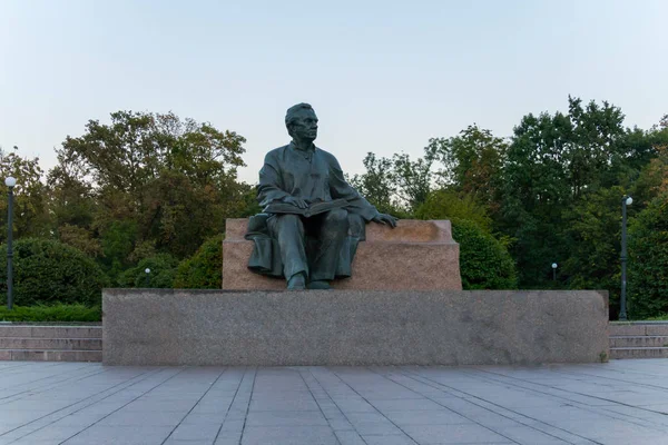 Moudrý muž sedí s otevřenou knihou na podstavci v parku se nachází socha — Stock fotografie
