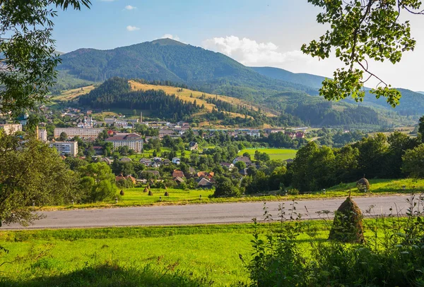 Eine moderne Stadt am Fuße eines Berges mit dichtem Wald, grünem Gras und blauem Himmel. masto für Erholung, Picknicks und Tourismus — Stockfoto