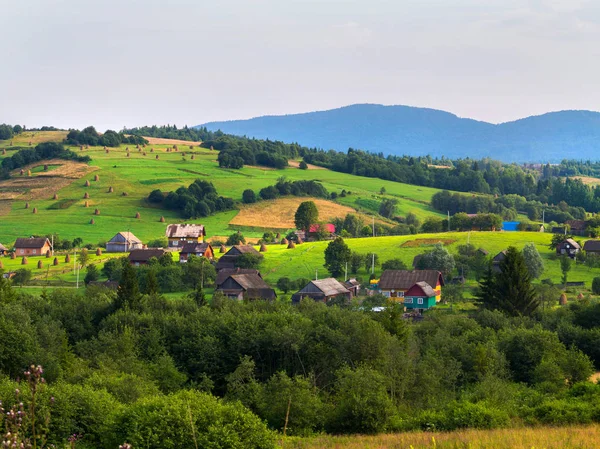 Schönes kleines Dorf. In der Ferne sind Heuhaufen zu sehen. und das alles vor dem Hintergrund des Berges — Stockfoto