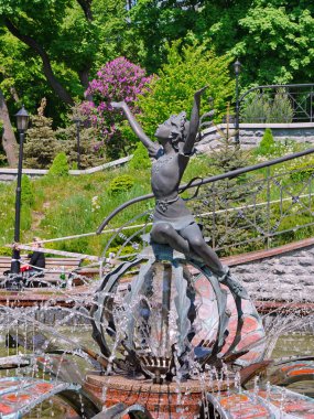 Bir top yeşil bir parkta bir kızı gösteren güzel bir çeşme. Yürüyüşleri için yer