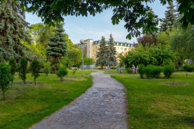yeşil park ve bir bankta oturan insanlar döşeli taş oluşan bir yol