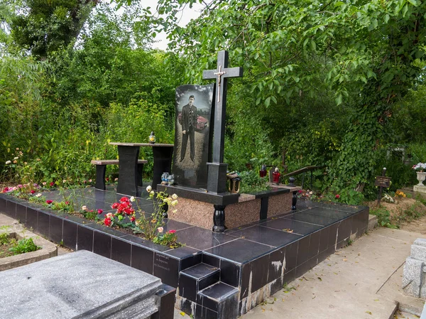 A large black monument with a cross. It shows a man in a suit and a red car behind him — Stock Photo, Image