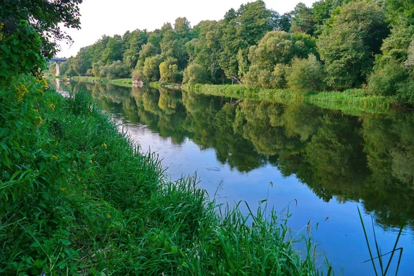 Egy ragyogó fű, a távolban egy híd és egy kis folyó partján — Stock Fotó