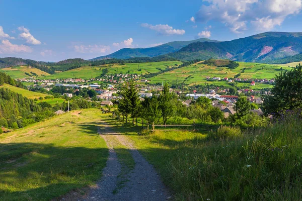 Die Straße, die zum Dorf führt, am Zaun vorbei — Stockfoto