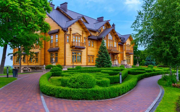 Una hermosa mansión de madera de cubiertas de pino y un parterre frente a ella — Foto de Stock