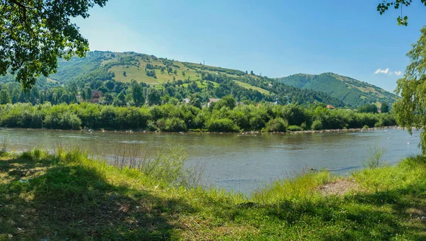 Швидка гірська річка з величезними каменями на своєму шляху, розділяючи два зелених пляжі — стокове фото