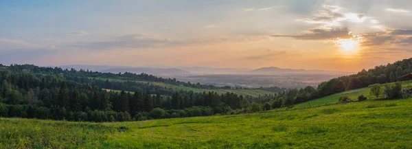 Solnedgång över ett panorama över berget kullar och byn i dalen — Stockfoto