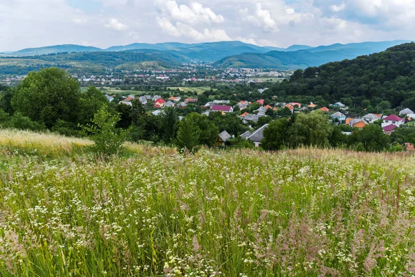 Un pequeño pueblo está envuelto en todas direcciones por un campo floreciente, bosques y montañas —  Fotos de Stock