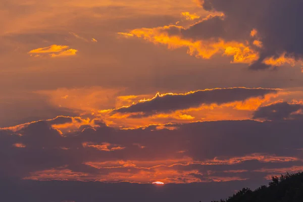 The beauty of the evening sky with clouds of red in the setting sun, a little more visible on the horizon — Stock Photo, Image