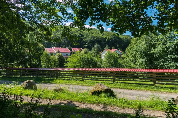 Carretera con una valla de madera contra el telón de fondo del complejo hotelero con techos de color rojo brillante —  Fotos de Stock