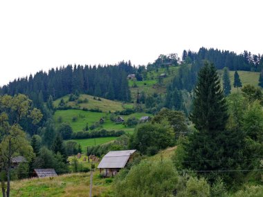 Yemyeşil ağaçlar ve çalılar arasında yamaç boyunca kaotik bir sırada yer alan küçük kırsal konutlarında.