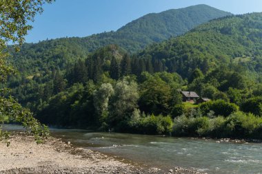 Sınırsız yeşil dağların arasında küçük kırsal konutlarında çerçevede nehir kıyısında taş