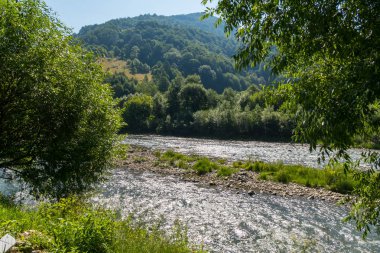 yeşil, nehrin yavaş onun iş ve uzaktan gökyüzünün bir parçası gevezelik ile kaplı dağlık arazi yamaçlar güzel bir manzara
