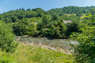Taş evler, bankalar ile sığ bir nehir boyunca dağınık