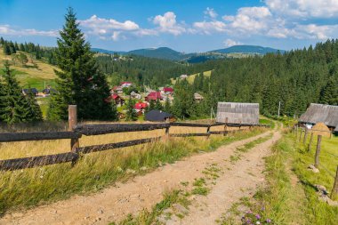 Kumlu toprak yol mesafe evler ahşap çitleri arasında çalışan kırsal kesimde.