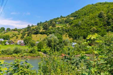 Arka planı küçük kırsal konutlarında ve yüksek yeşil dağların bir hızlı, şeffaf nehir