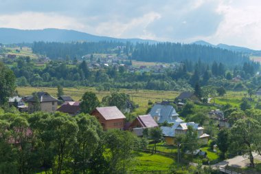 Bir güzel ve rahat köy puslu bir gökyüzü arka planı görkemli Dağları'nın eteklerinde yer alır