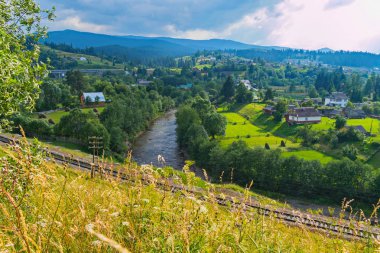 çayır ve köy arka plan üzerinde Nehri arasında demiryolu