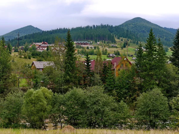 Ein Panorama bewaldeter Berge in der Nähe des Dorfes mit Hotels in der Nähe des Gebirgsflusses — Stockfoto