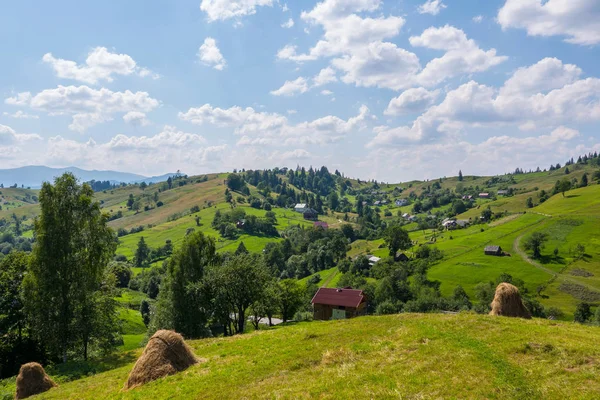 Yeşil dağ küçük kırsal evleri ve banklar ile beyaz bulutlar mavi gökyüzü ile düz
